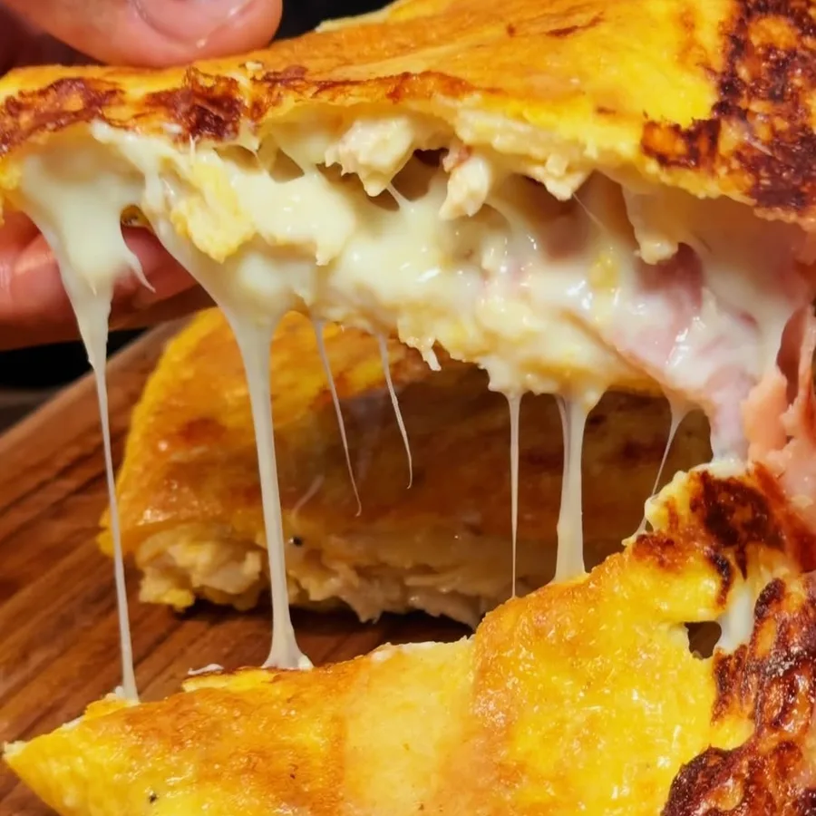 Tortilla de papa rellena recién partida, con el queso derretido estirándose