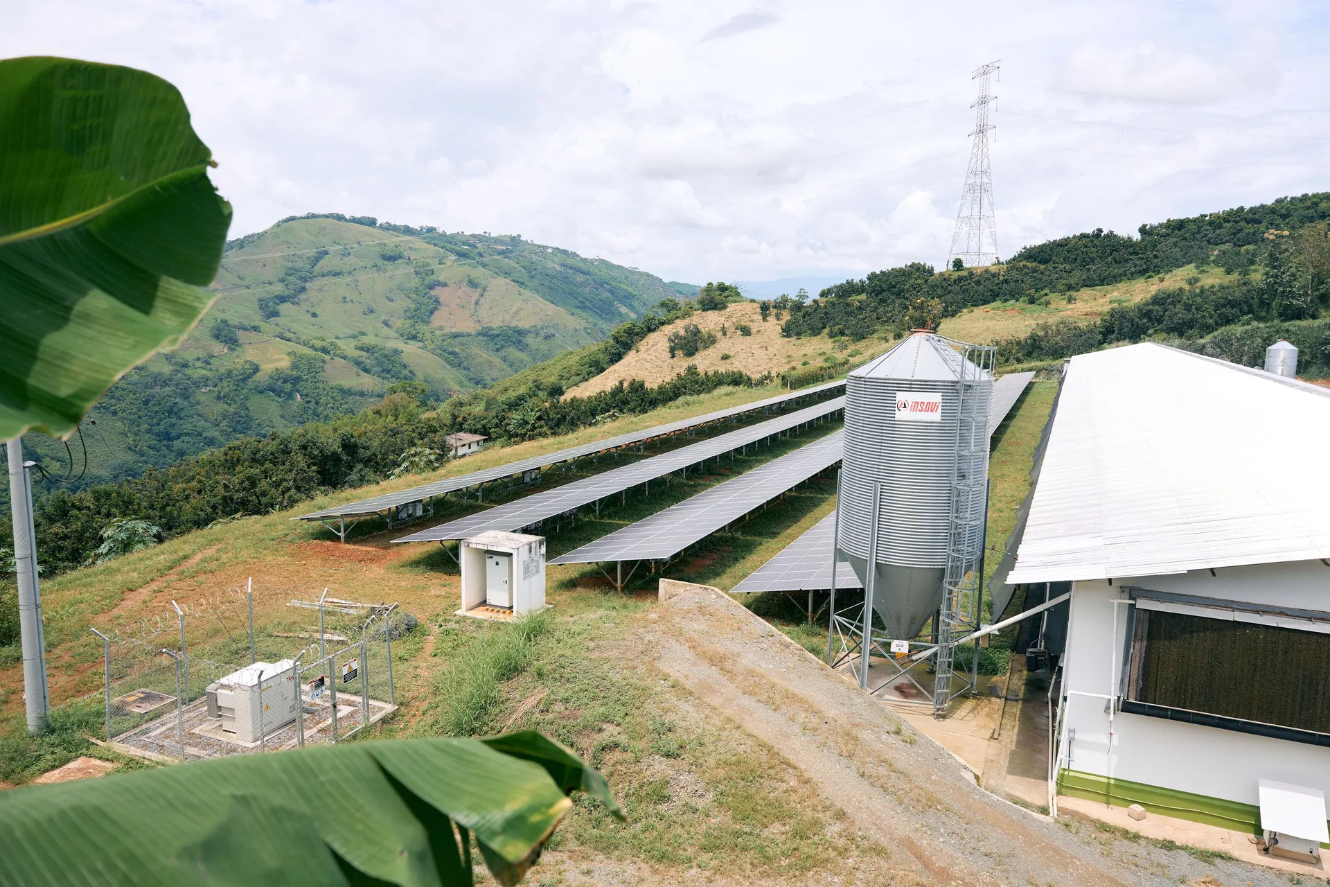 Galpones, silo y paneles solares de la operación, rodeados de montañas