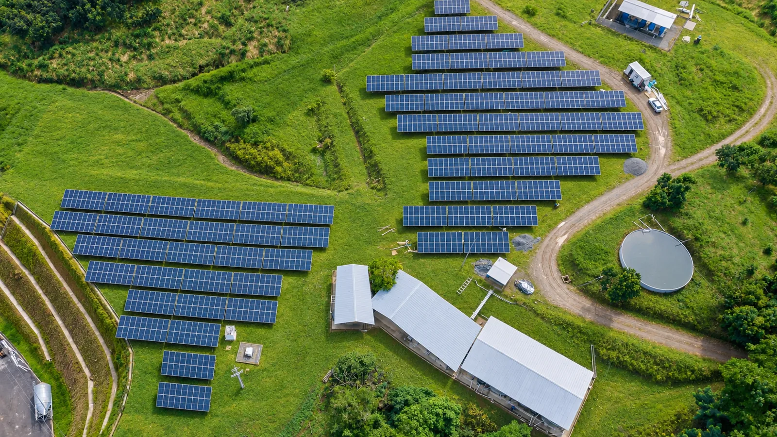 Vista aérea de los paneles solares de la granja entre montañas verdes