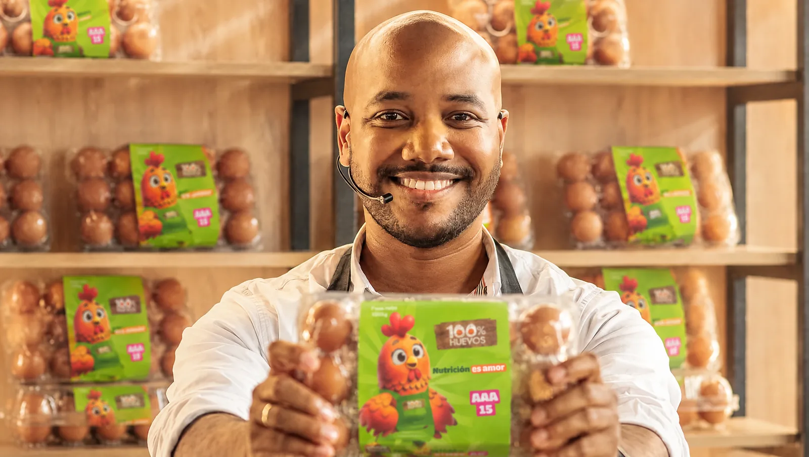 Persona sonriendo mientras muestra un empaque de 15 huevos 100% Huevos en una cocina